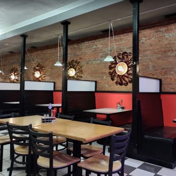 Interior of El Mexican Restaurant with wooden tables, red booths, brick walls, and decorative sun mirrors.
