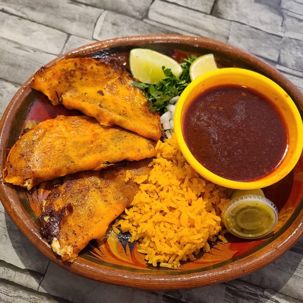 Three golden-brown birria tacos with rice, lime, cilantro, onions, and a side of consommé.