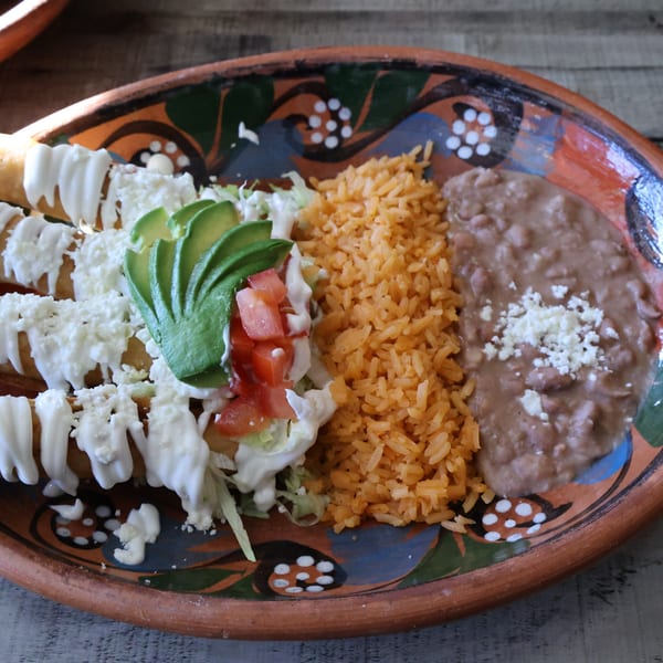 El Mexican Restaurant's flautas with rice, refried beans, avocado, and sour cream on a colorful plate.