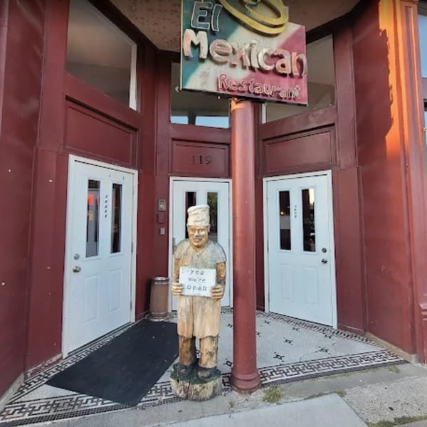 El Mexican Restaurant entrance with a wooden chef statue holding an "Open" sign.